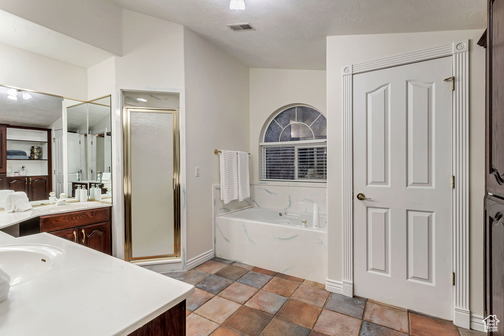 Bathroom with tile floors, shower with separate bathtub, a textured ceiling, and vanity with extensive cabinet space