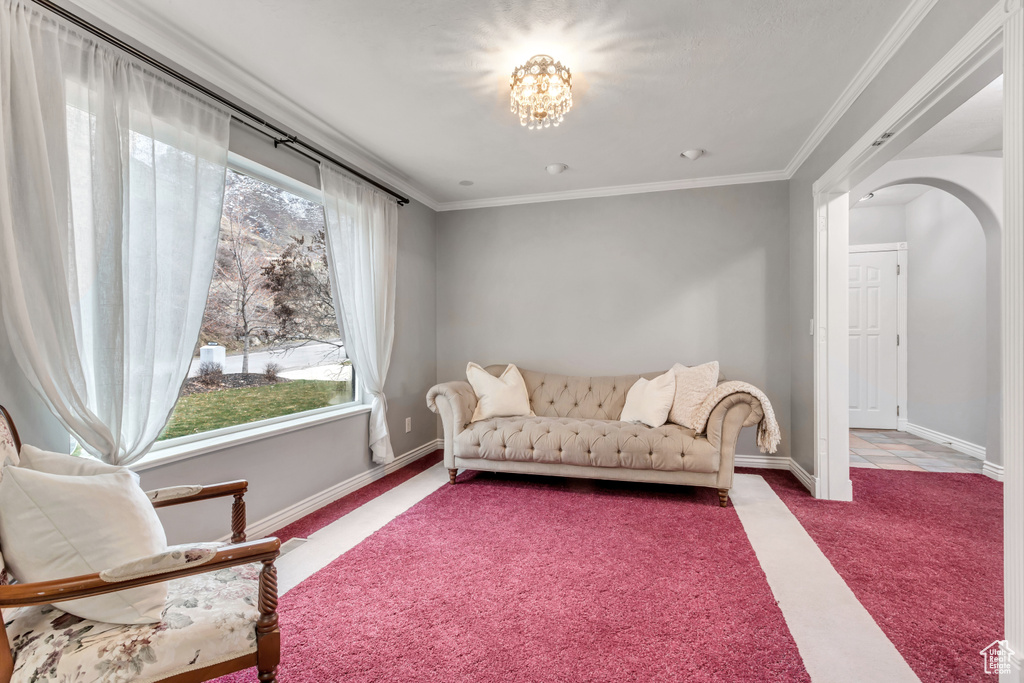 Living area featuring a wealth of natural light, light colored carpet, a notable chandelier, and crown molding