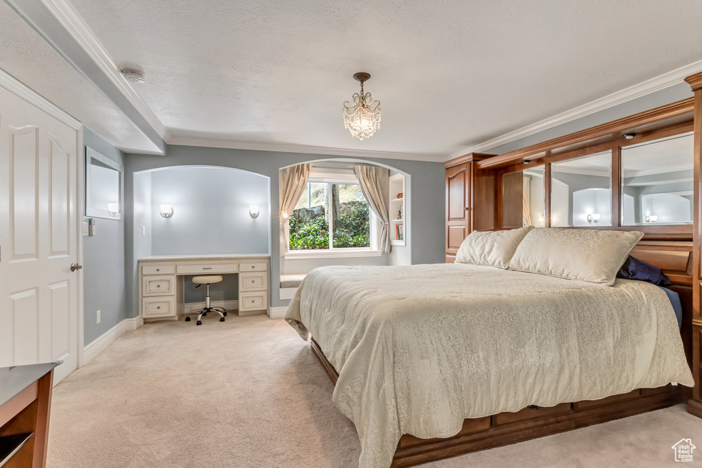 Bedroom featuring an inviting chandelier, light colored carpet, and ornamental molding