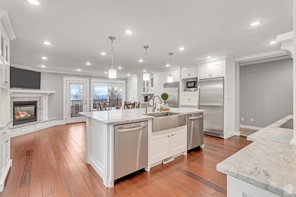 Kitchen with light wood-type flooring, white cabinetry, sink, an island with sink, and appliances with stainless steel finishes