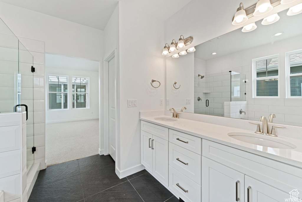 Bathroom with dual sinks, a shower with door, tile floors, and oversized vanity