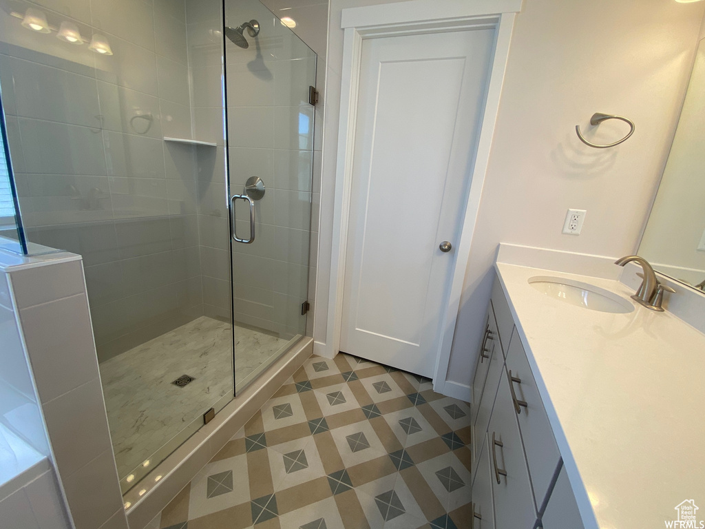Bathroom with tile floors, oversized vanity, and a shower with shower door