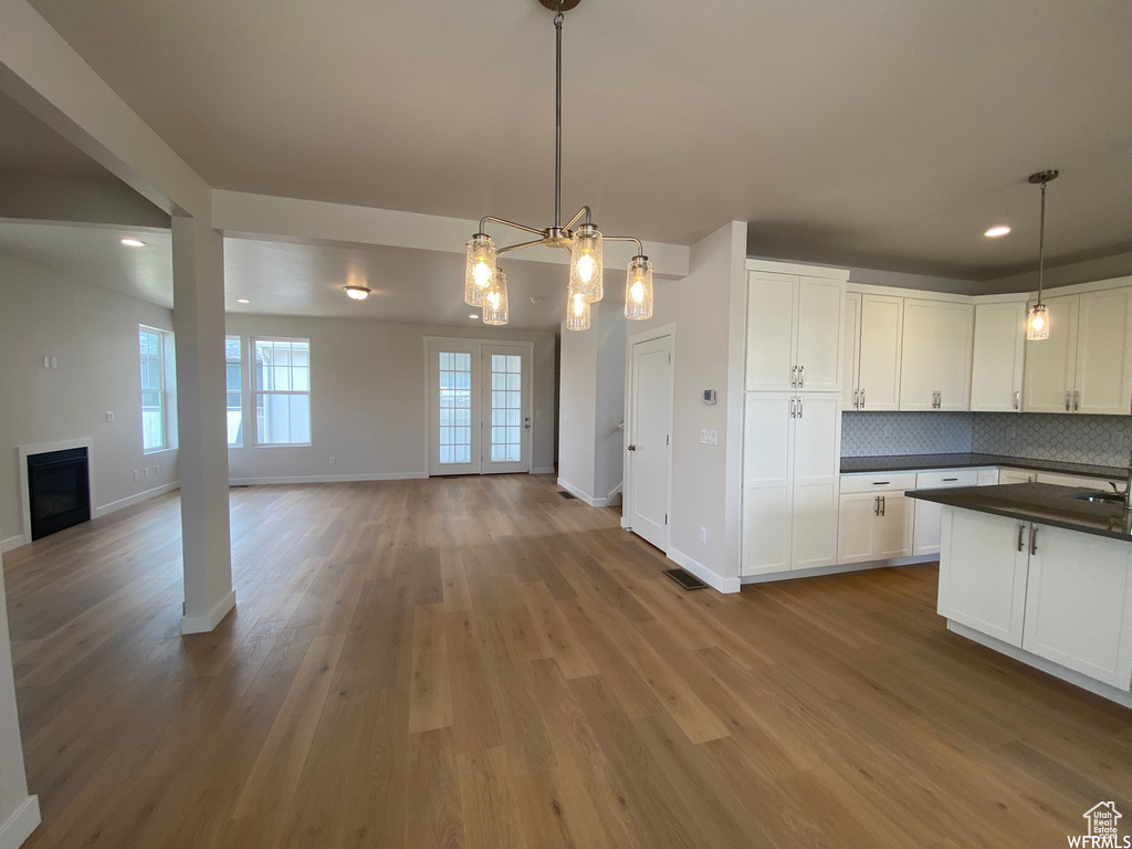 Kitchen featuring white cabinets, hanging light fixtures, and hardwood / wood-style floors