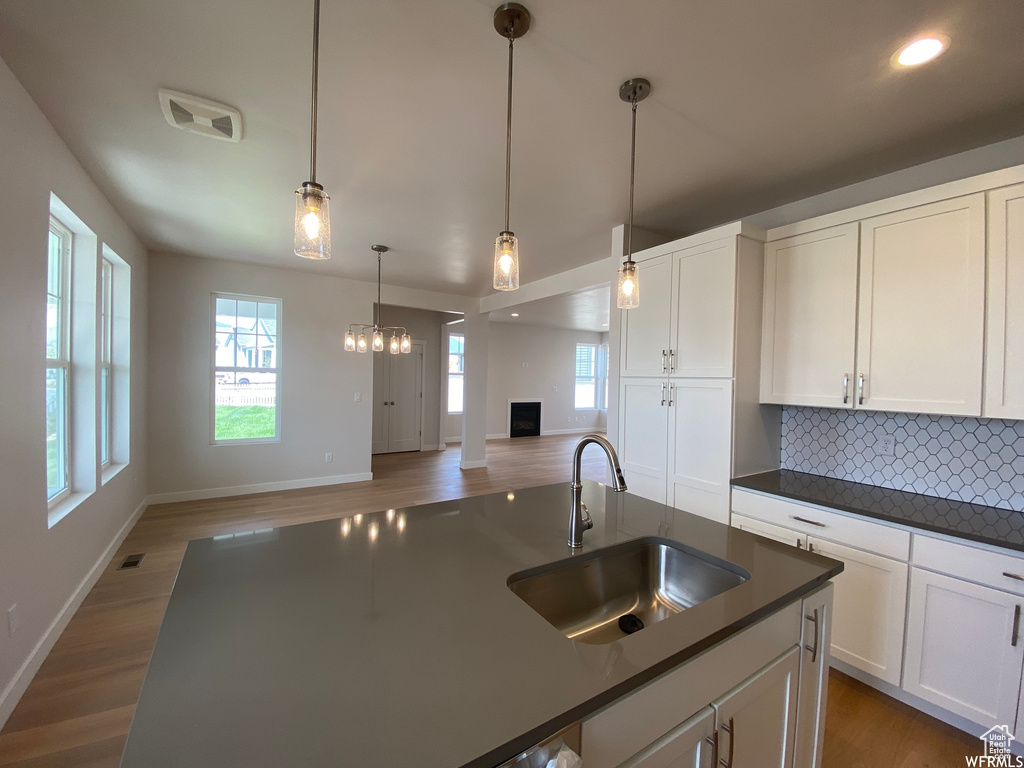 Kitchen featuring a notable chandelier, sink, hardwood / wood-style floors, and backsplash