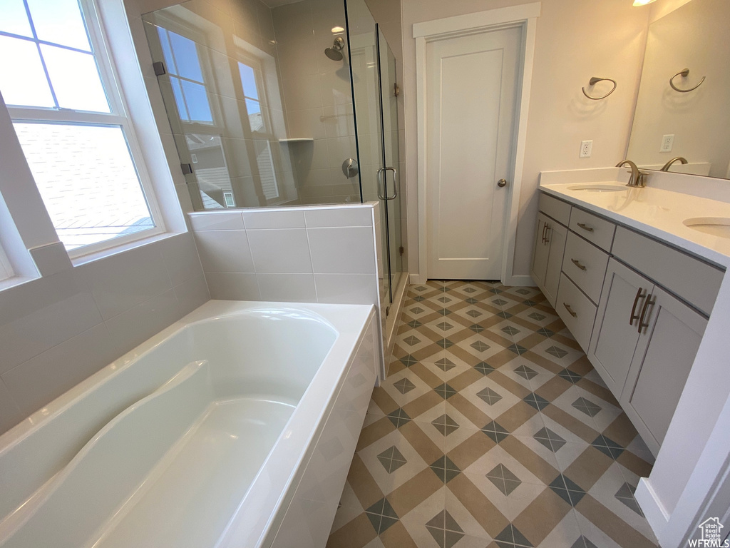 Bathroom featuring dual bowl vanity, tile flooring, and shower with separate bathtub