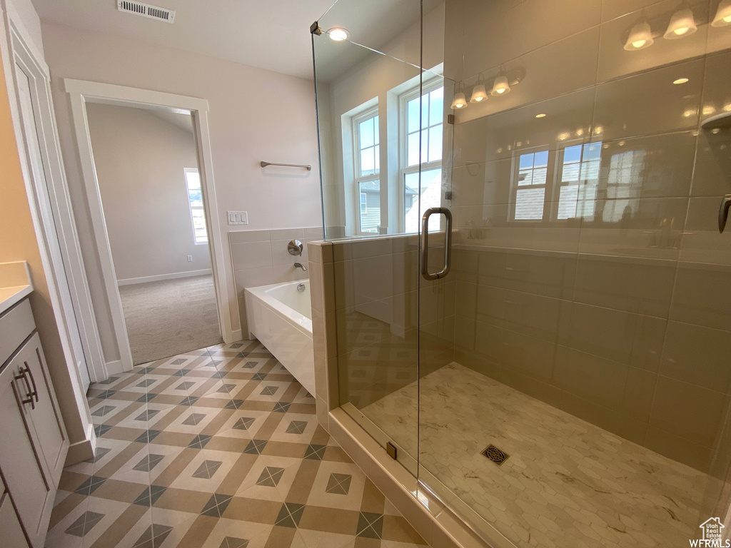 Bathroom with independent shower and bath, vanity, and tile flooring