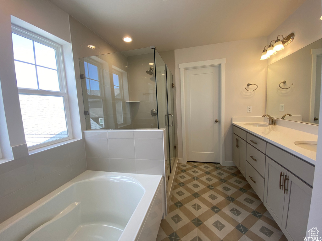 Bathroom with double sink vanity, tile flooring, and plus walk in shower