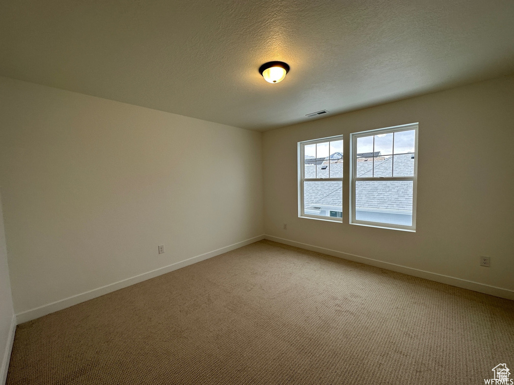 Spare room featuring light carpet and a textured ceiling
