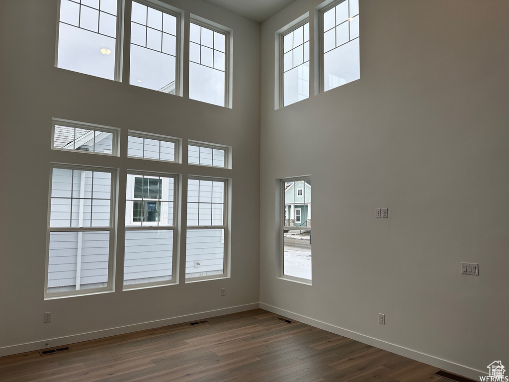Empty room with dark hardwood / wood-style flooring and a high ceiling