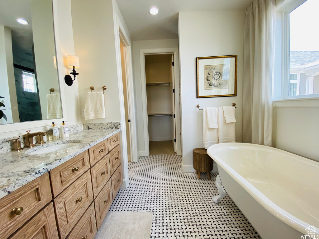 Bathroom with large vanity, a washtub, and tile flooring