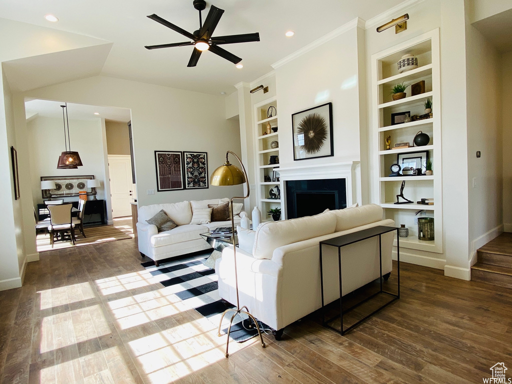 Living room featuring dark hardwood / wood-style floors, ceiling fan, built in features, and lofted ceiling