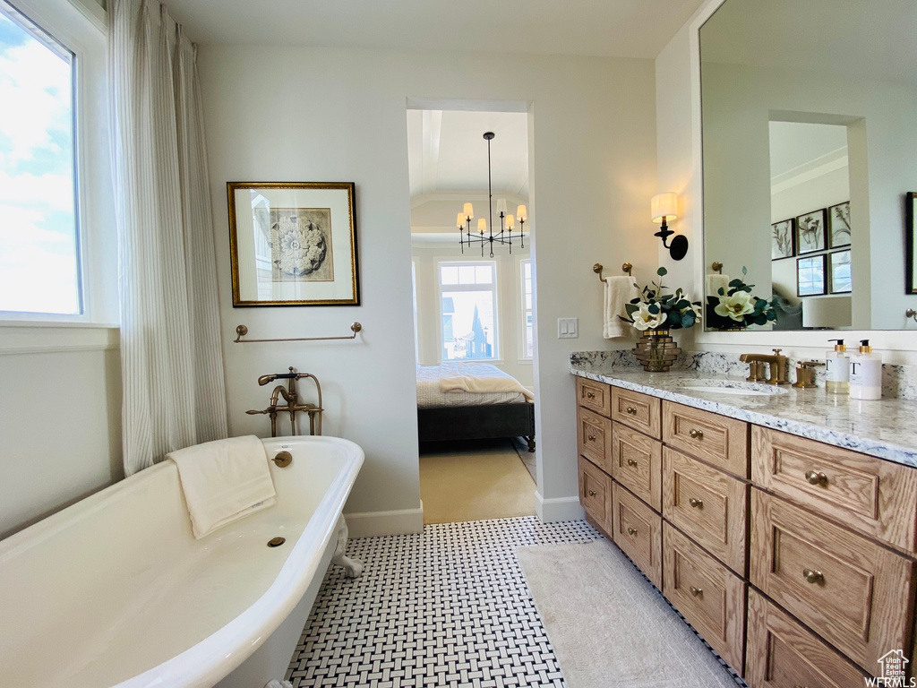 Bathroom with vanity, a bathing tub, ornamental molding, an inviting chandelier, and tile flooring