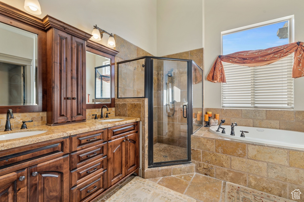 Bathroom featuring shower with separate bathtub, dual vanity, and tile flooring
