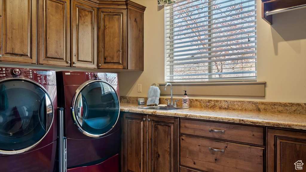 Clothes washing area with a healthy amount of sunlight, cabinets, sink, and separate washer and dryer