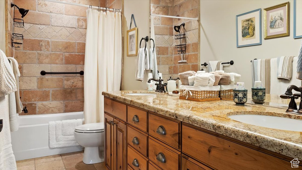 Full bathroom with dual sinks, tile floors, large vanity, shower / tub combo, and toilet