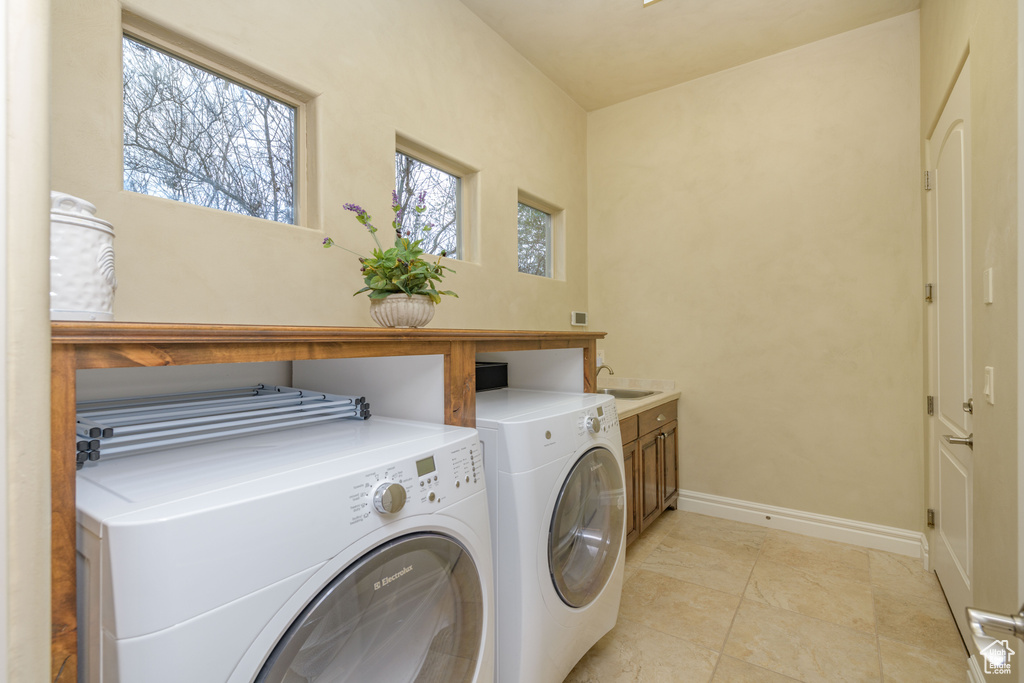Laundry room featuring cabinets, sink, light tile floors, and washing machine and clothes dryer