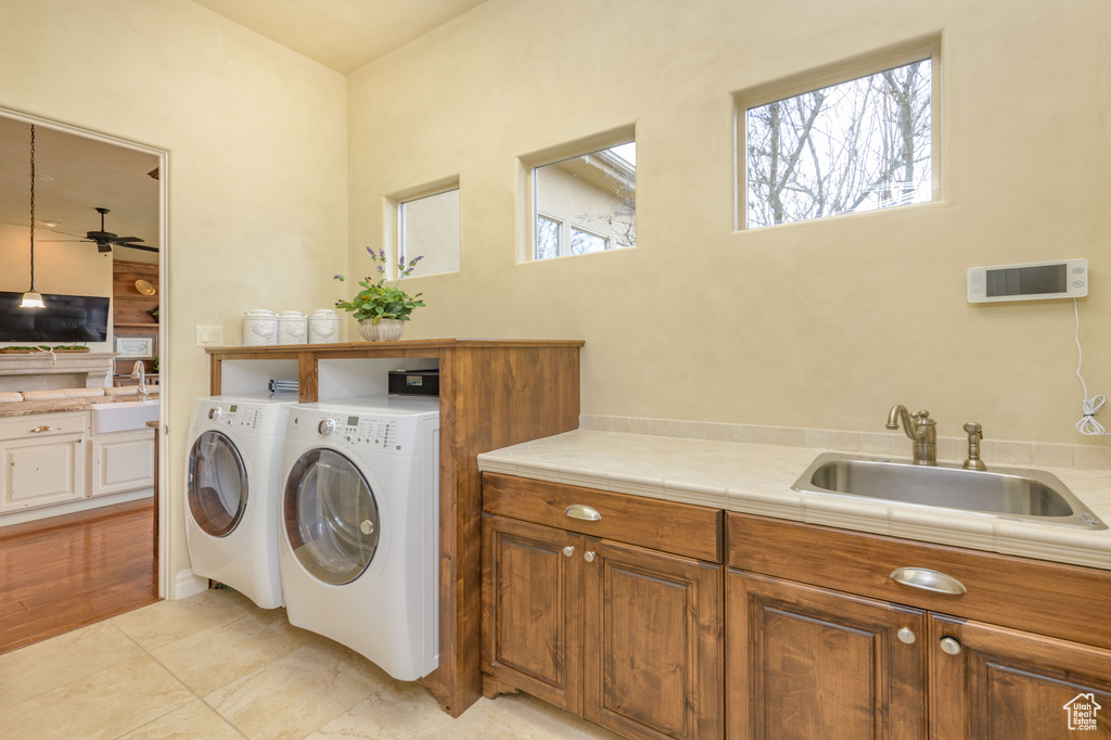 Laundry area featuring light tile floors, ceiling fan, washing machine and dryer, cabinets, and sink