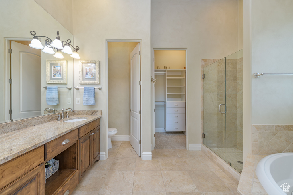 Full bathroom featuring separate shower and tub, a high ceiling, oversized vanity, toilet, and tile floors