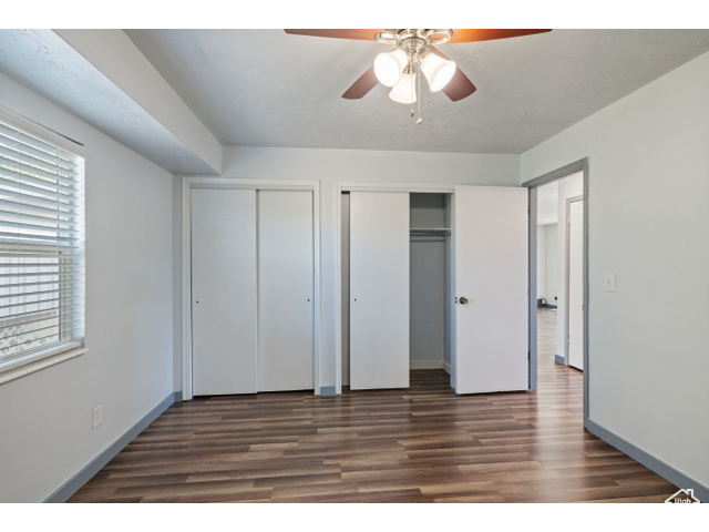 Unfurnished bedroom with dark hardwood / wood-style floors, two closets, and ceiling fan