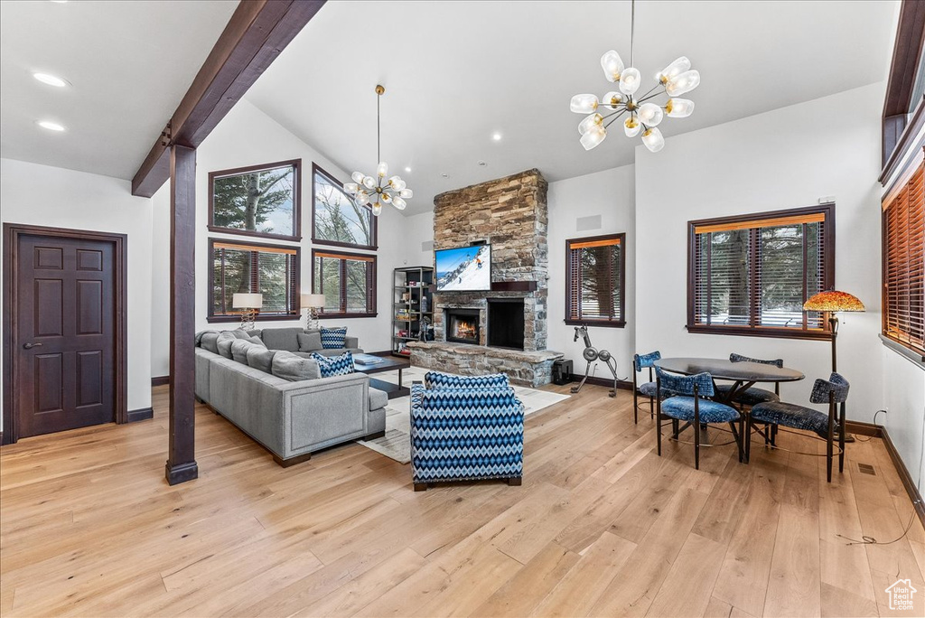 Living room featuring a stone fireplace, plenty of natural light, light hardwood / wood-style floors, and a chandelier