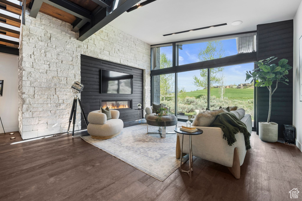 Living room featuring floor to ceiling windows, wood finished floors, and a glass covered fireplace