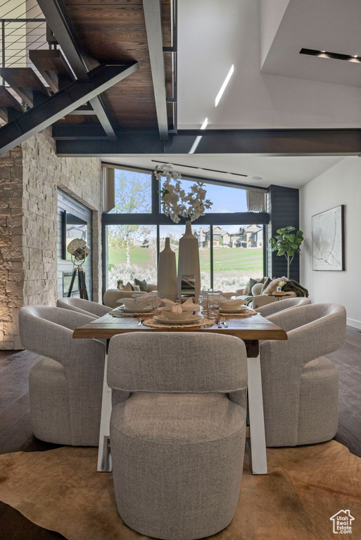 Living room featuring plenty of natural light, stairs, beamed ceiling, and wood finished floors