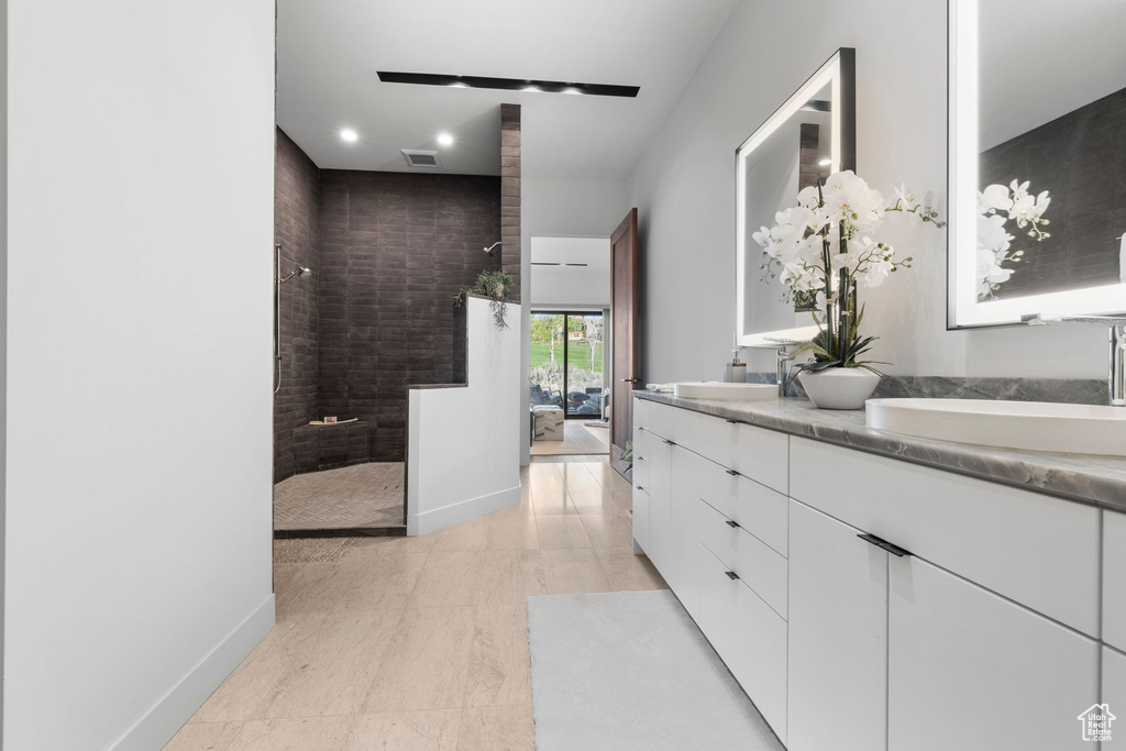 Full bath featuring double vanity, a walk in shower, recessed lighting, and baseboards
