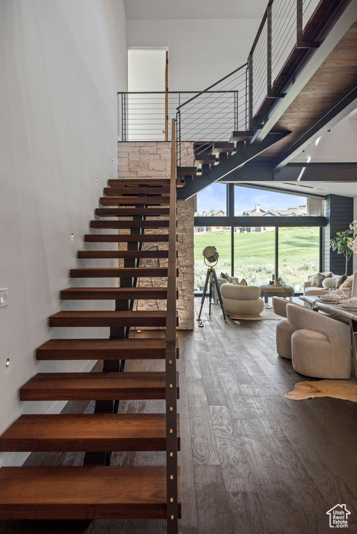 Stairway with wood finished floors and a towering ceiling
