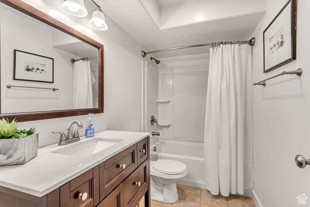 Full bathroom with tile floors, toilet, shower / bath combo with shower curtain, and vanity