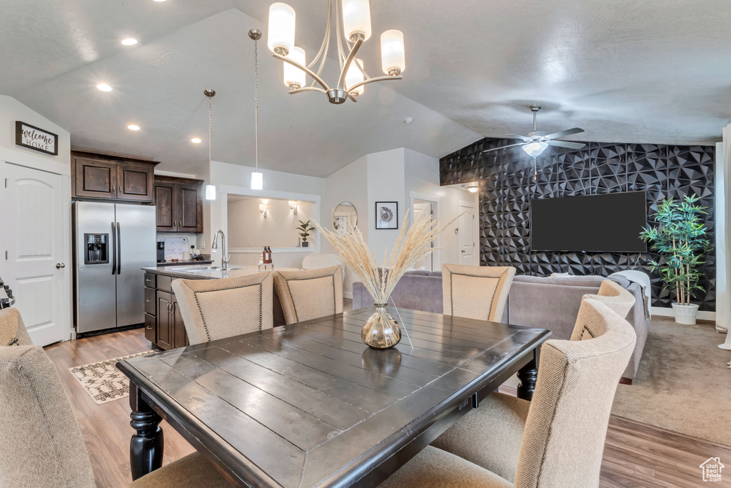 Carpeted dining area with ceiling fan with notable chandelier, lofted ceiling, and sink