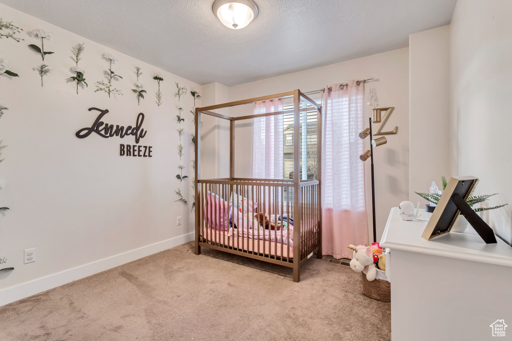 Bedroom featuring a crib and light carpet