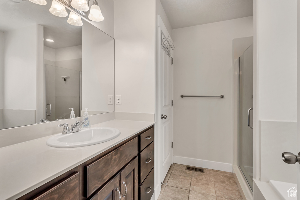 Bathroom featuring a shower with door, tile floors, and vanity with extensive cabinet space