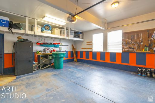 Garage with black refrigerator, a workshop area, and a garage door opener