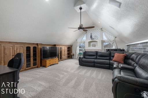 Living room featuring light carpet, vaulted ceiling, and ceiling fan