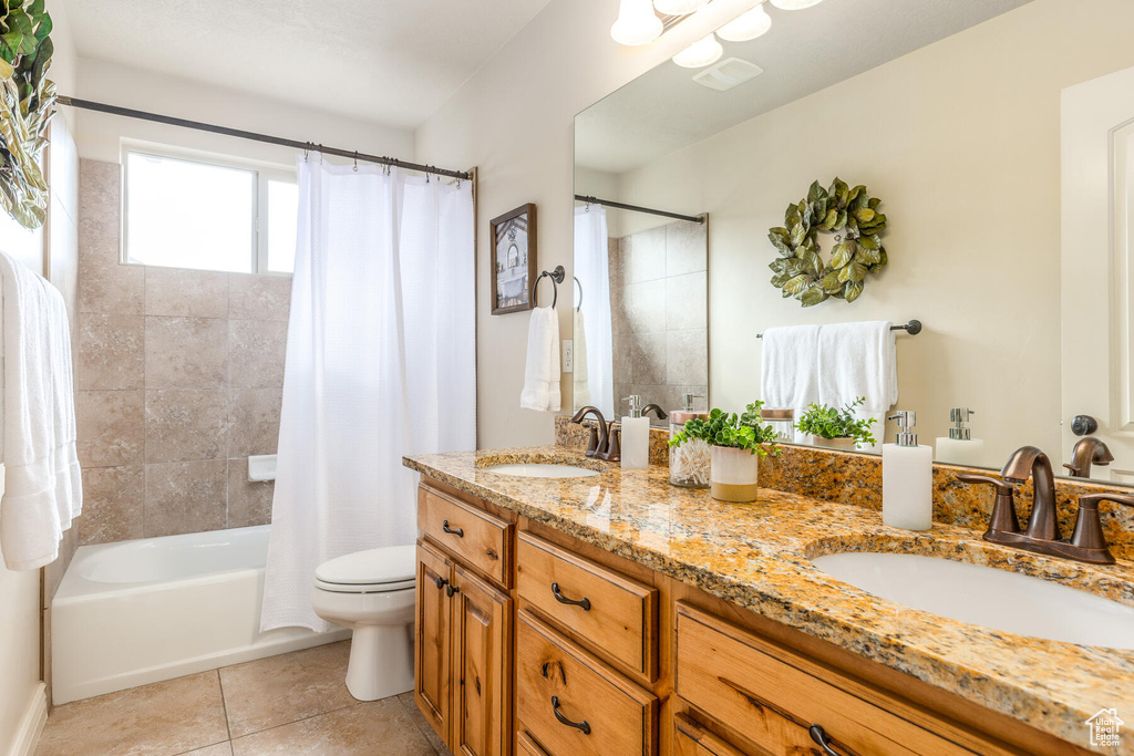 Full bathroom with shower / tub combo with curtain, dual bowl vanity, tile flooring, and toilet