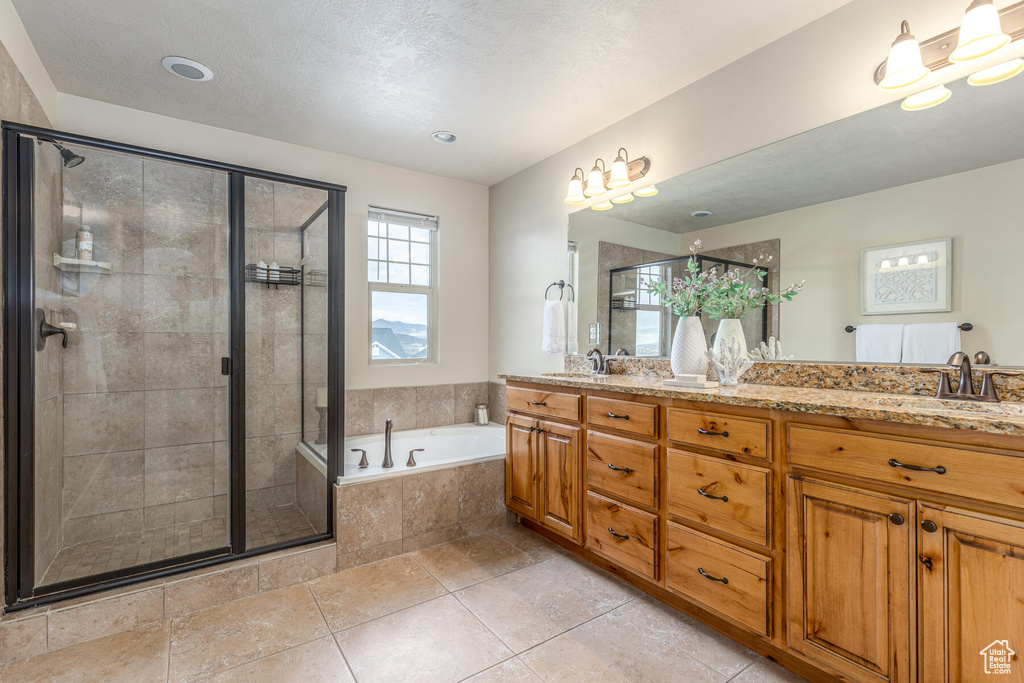 Bathroom featuring tile floors, dual vanity, a textured ceiling, and shower with separate bathtub