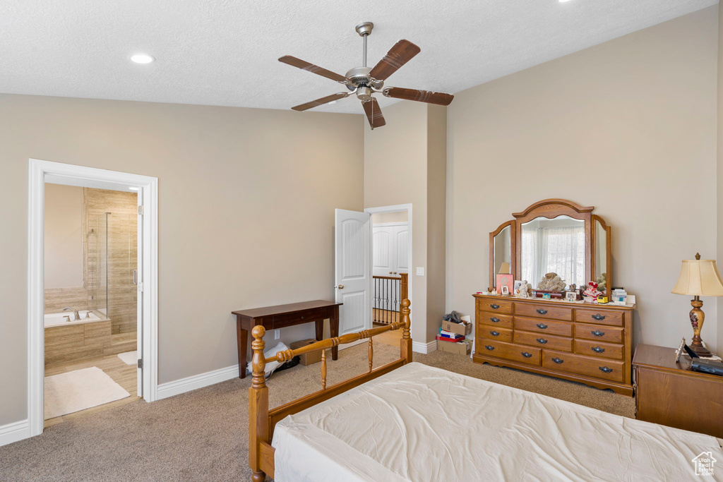Bedroom with ensuite bathroom, ceiling fan, light colored carpet, and lofted ceiling