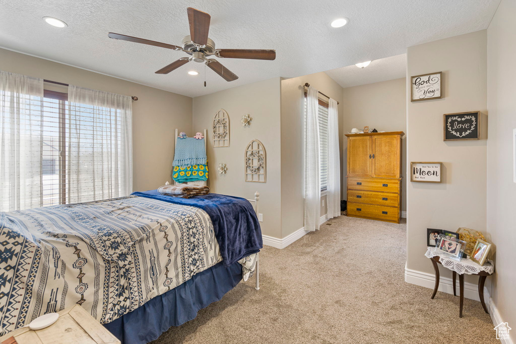 Bedroom featuring ceiling fan, light colored carpet, and a textured ceiling