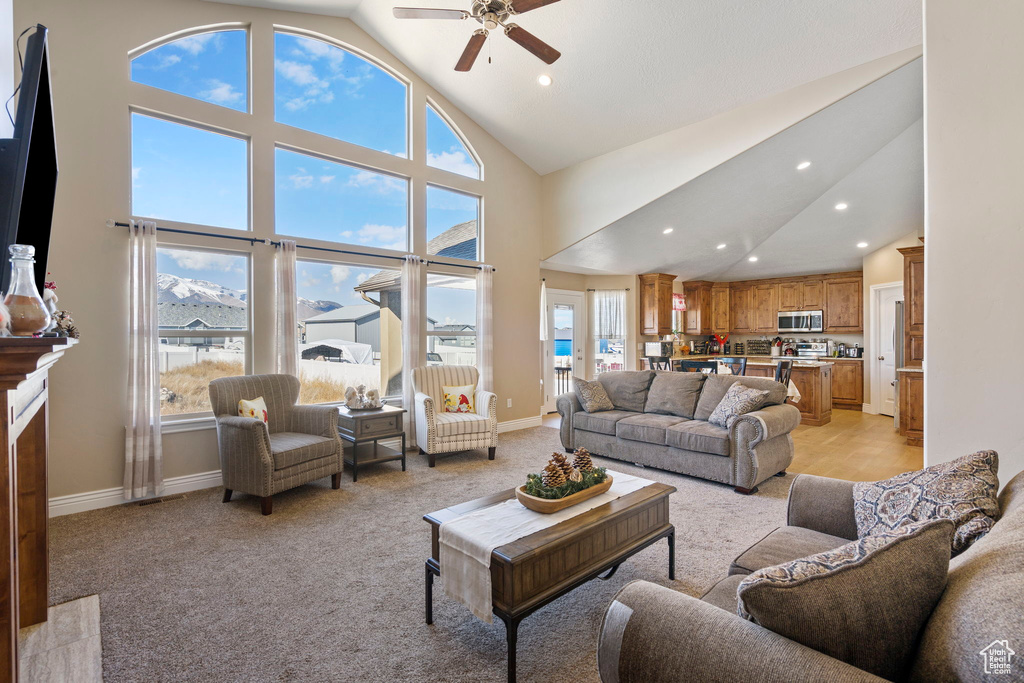 Carpeted living room featuring plenty of natural light, high vaulted ceiling, a tile fireplace, and ceiling fan