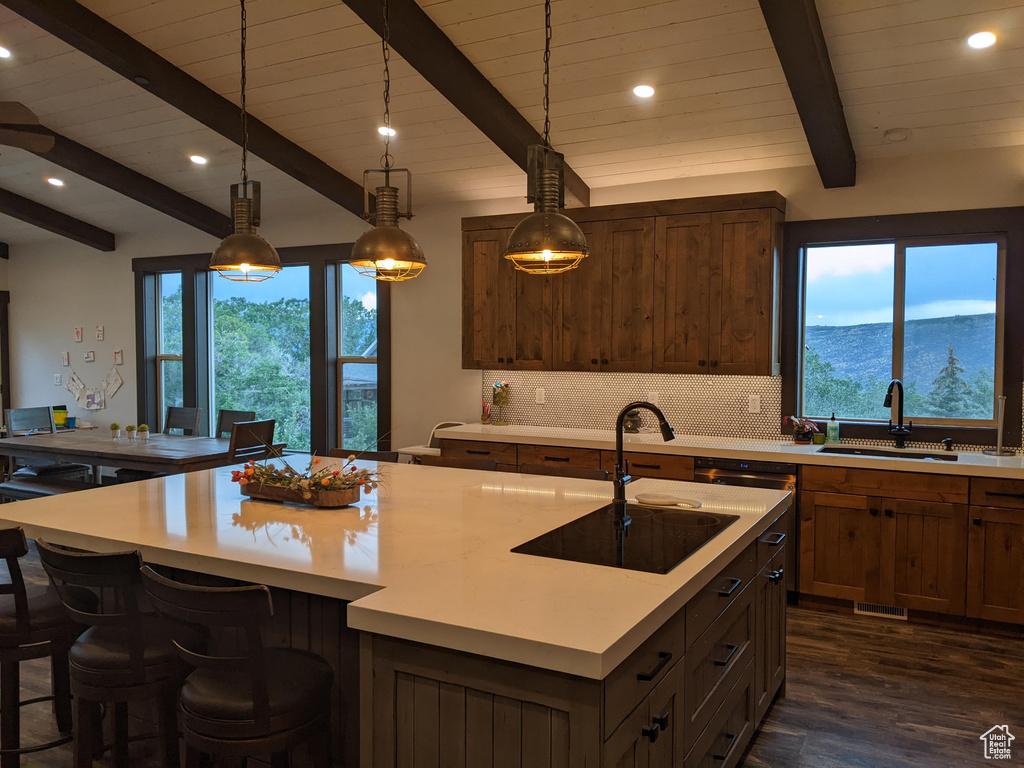 Kitchen with a center island with sink, decorative light fixtures, a wealth of natural light, and sink