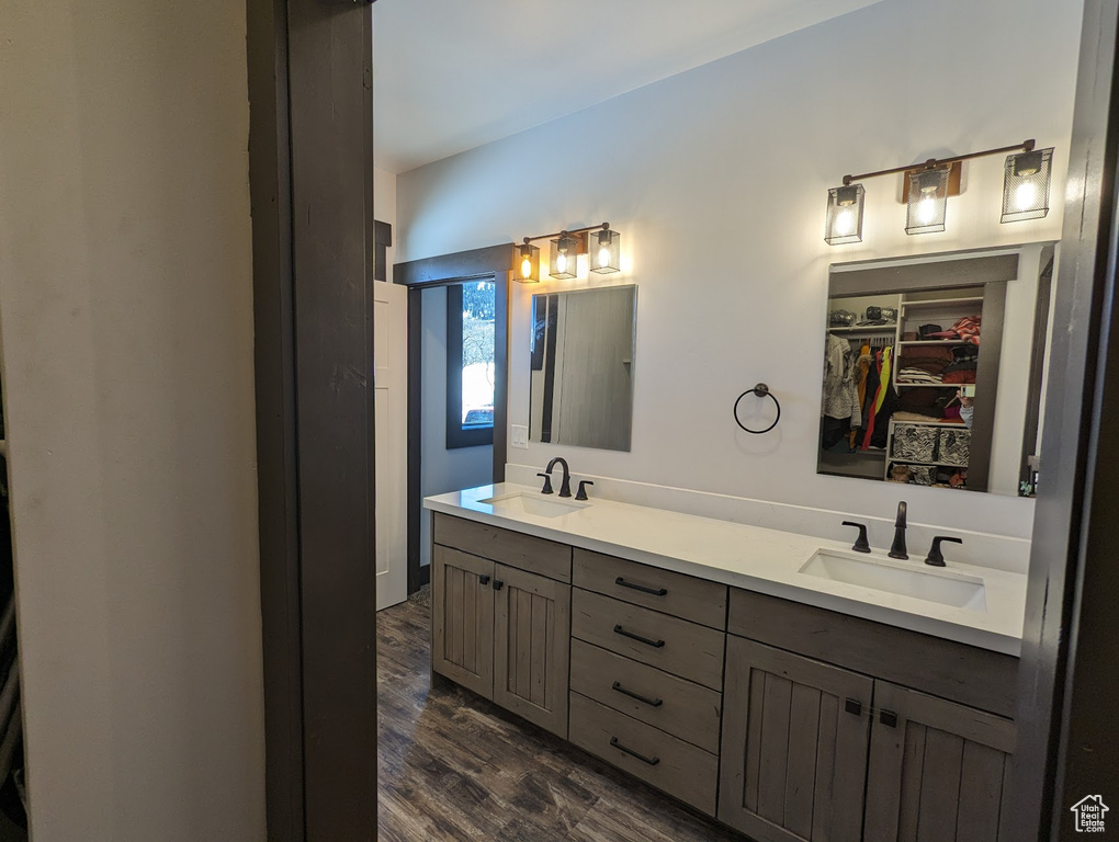 Bathroom featuring hardwood / wood-style floors, vanity with extensive cabinet space, and double sink