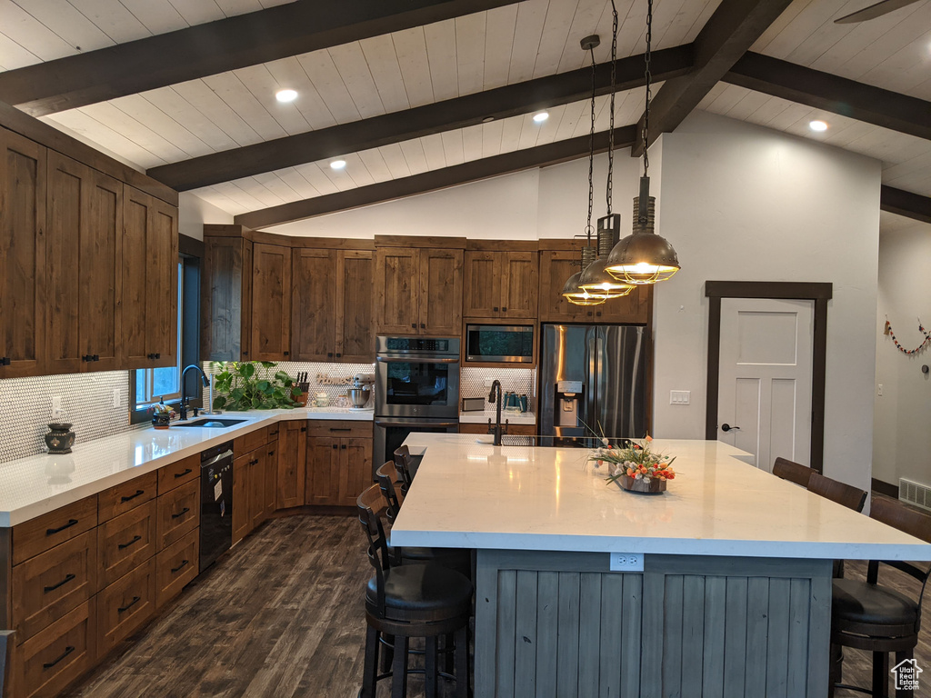 Kitchen with a kitchen island, dark wood-type flooring, sink, stainless steel appliances, and pendant lighting