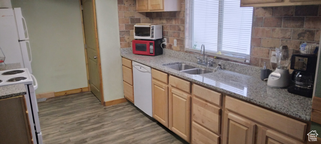 Kitchen featuring light stone counters, light wood-type flooring, tasteful backsplash, sink, and white appliances