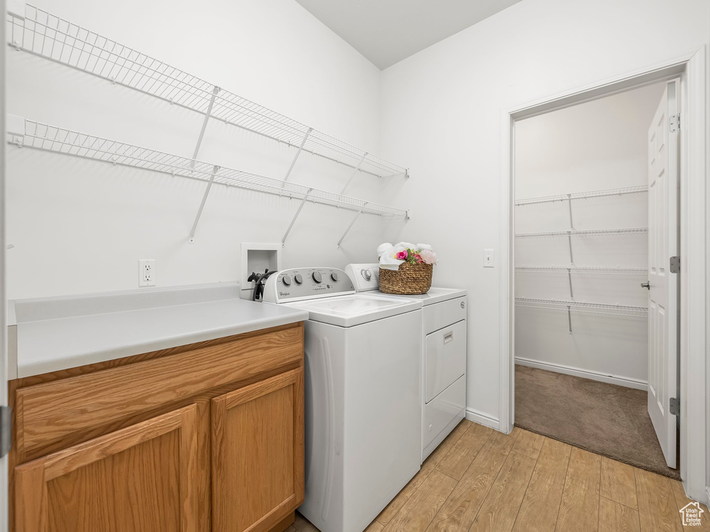 Laundry room with washer hookup, cabinets, light hardwood / wood-style floors, and washing machine and clothes dryer