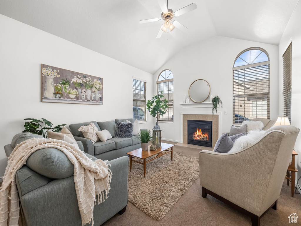 Living room featuring dark carpet, plenty of natural light, ceiling fan, and a tile fireplace