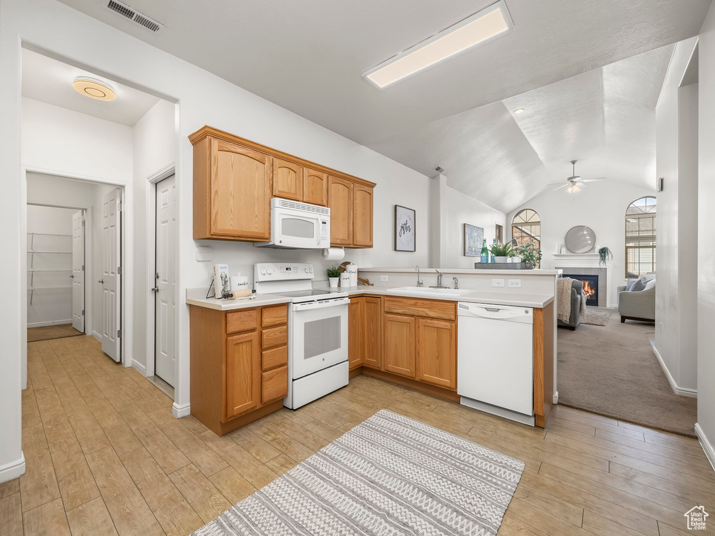Kitchen featuring vaulted ceiling, white appliances, kitchen peninsula, light hardwood / wood-style flooring, and ceiling fan