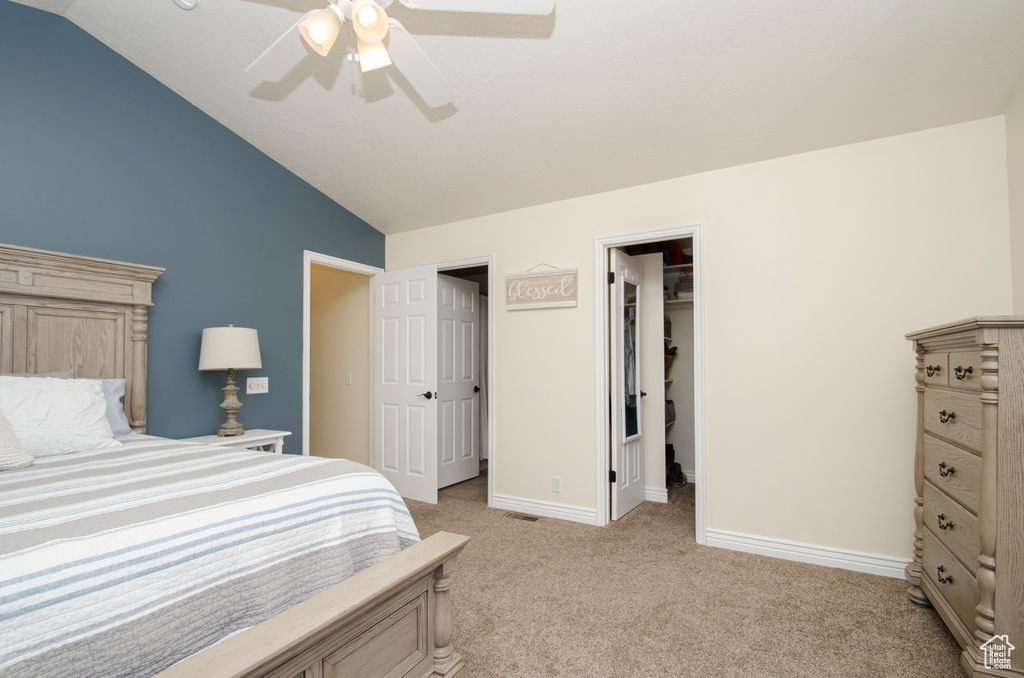 Carpeted bedroom featuring a spacious closet, vaulted ceiling, a closet, and ceiling fan