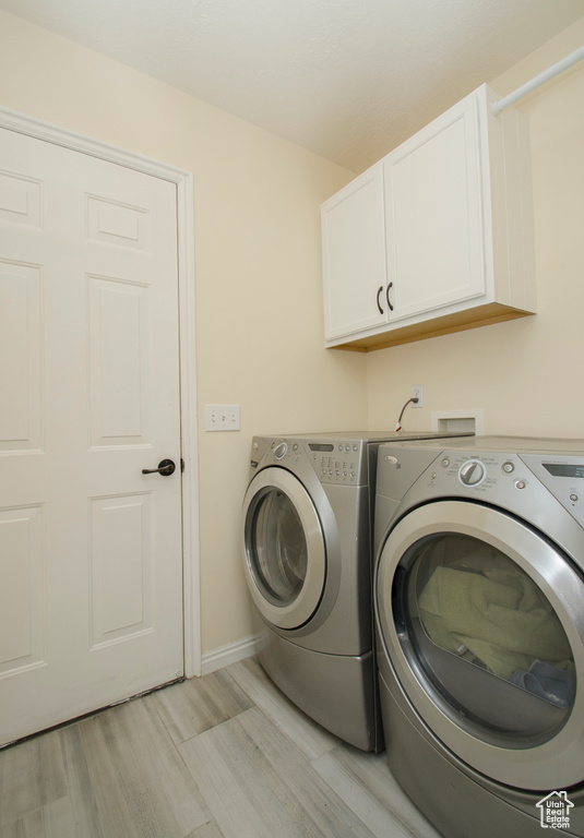 Washroom featuring cabinets, light hardwood / wood-style flooring, and separate washer and dryer