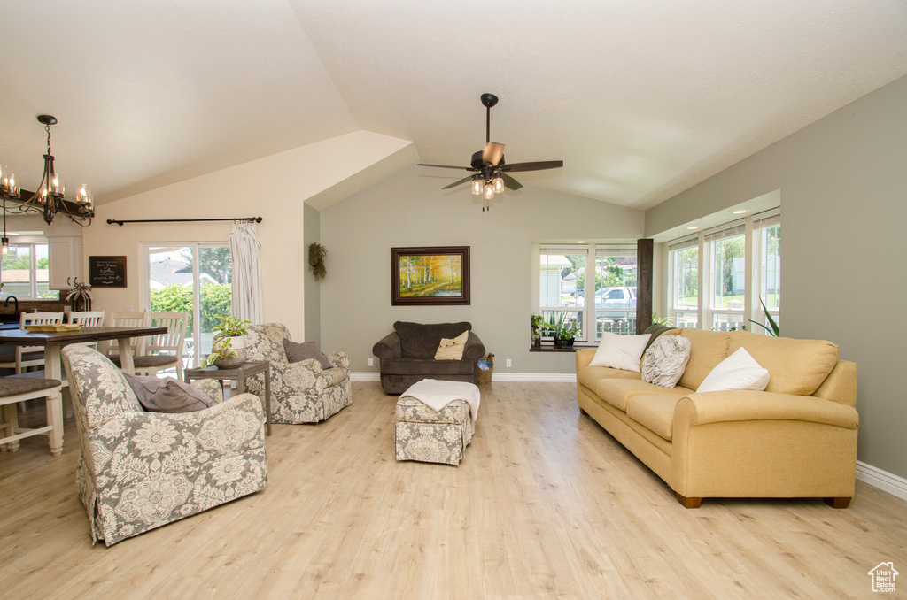 Living room featuring vaulted ceiling, ceiling fan with notable chandelier, and light hardwood / wood-style flooring
