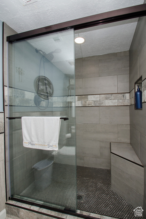 Bathroom featuring a shower with door and a textured ceiling